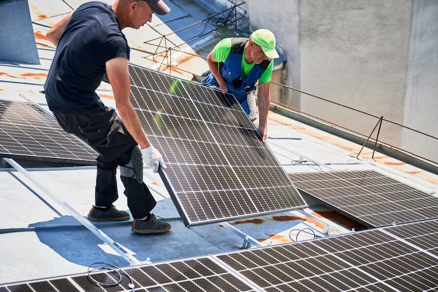 Technici usazují fotovoltaický panel na střešní konstrukci